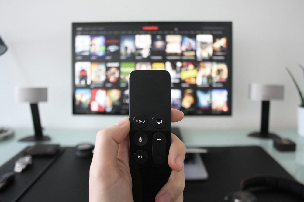 Person holding TV remote in front of TV screen