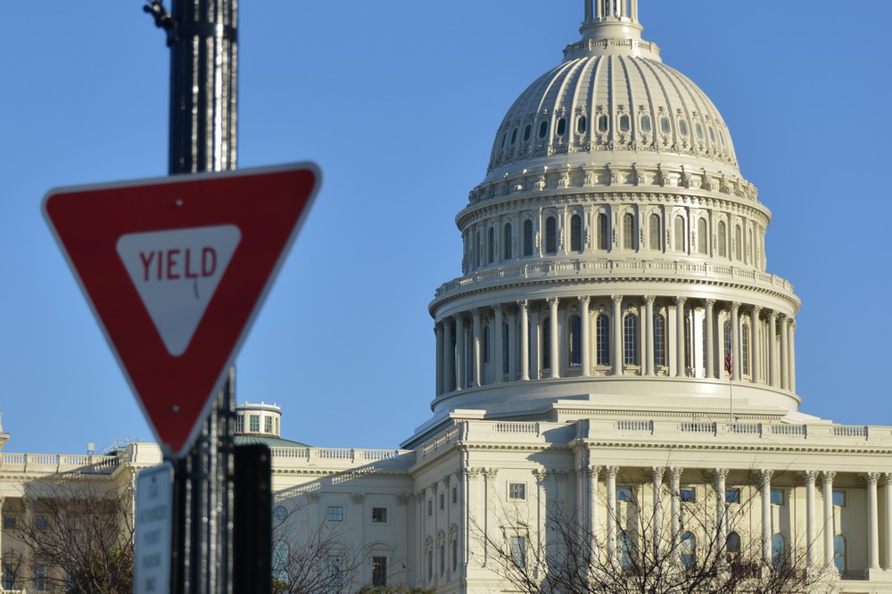 The United States capitol building with a yield sign in the foreground