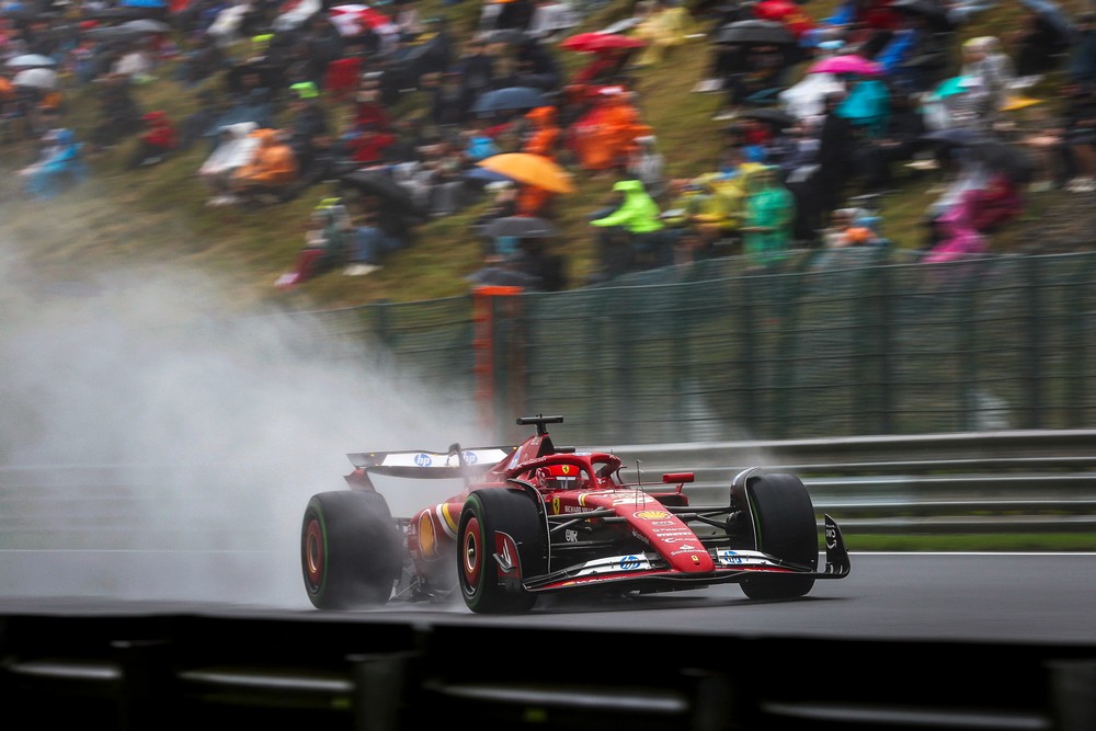 Charles Leclerc races down a straight with spray flowing behind the car during a damp 2024 Belgian Grand Prix practice session