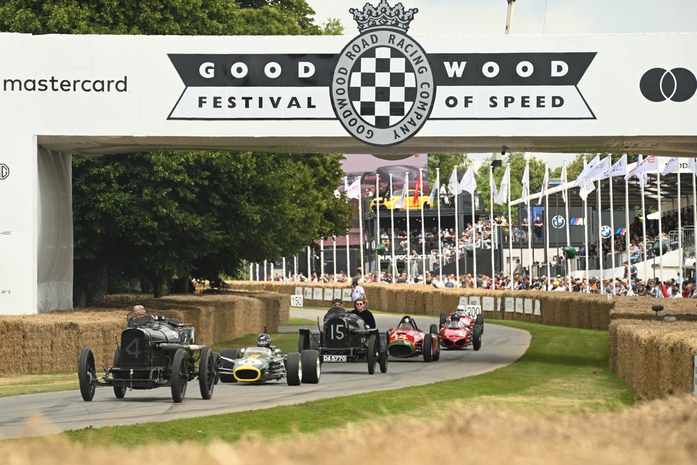 Six grand prix cars from various years parade up the hill at the 2024 Goodwood Festival of Speed