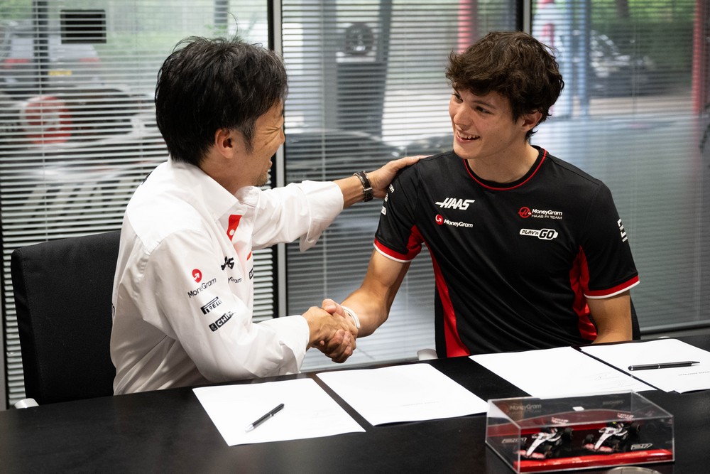 Haas team principal Akao Komatsu (left) shakes hands with Oliver Bearman (right) after signing a contract