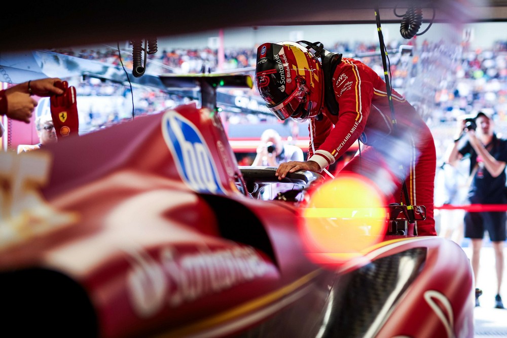 Carlos Sainz climbing into his Ferrari in the garage at the 2024 Belgian Grand Prix