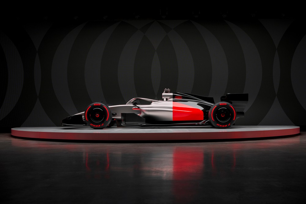 A grey, red, and black liveried concept car sits atop a platform during the Audi launch event